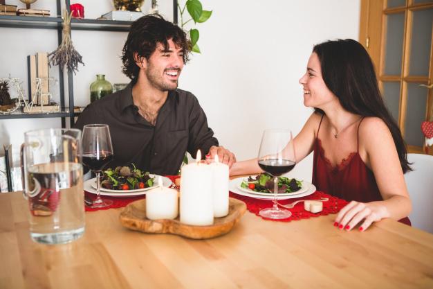 pareja-sentada-mesa-comer-sonriendo_23-2147596058